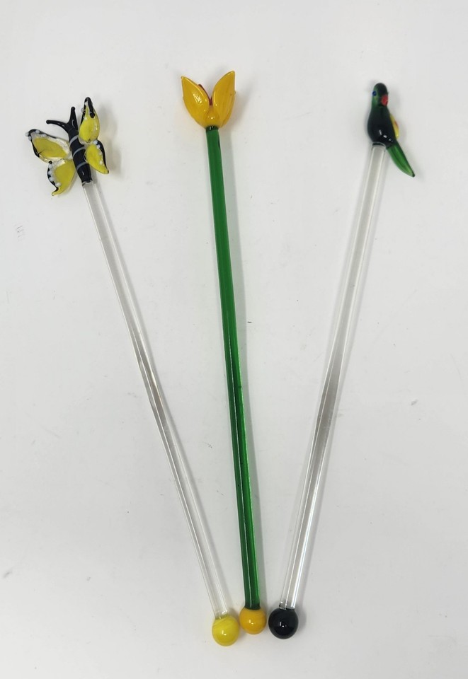 Three individually hand-blown stirrers each shaped as a different creature — tulip, parrot, and butterfly — are tiny sculptures that happen to mix your drink.