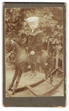 Fotografie junger Knabe auf seinem Schaukelpferd 