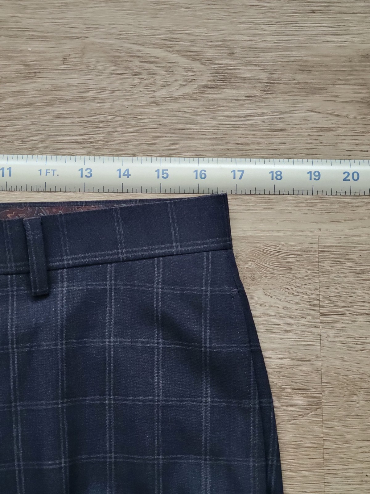 Navy blue plaid men’s flat front dress pants, size 32W x 30L, with white cuff and placket buttons, laid flat on wooden surface.