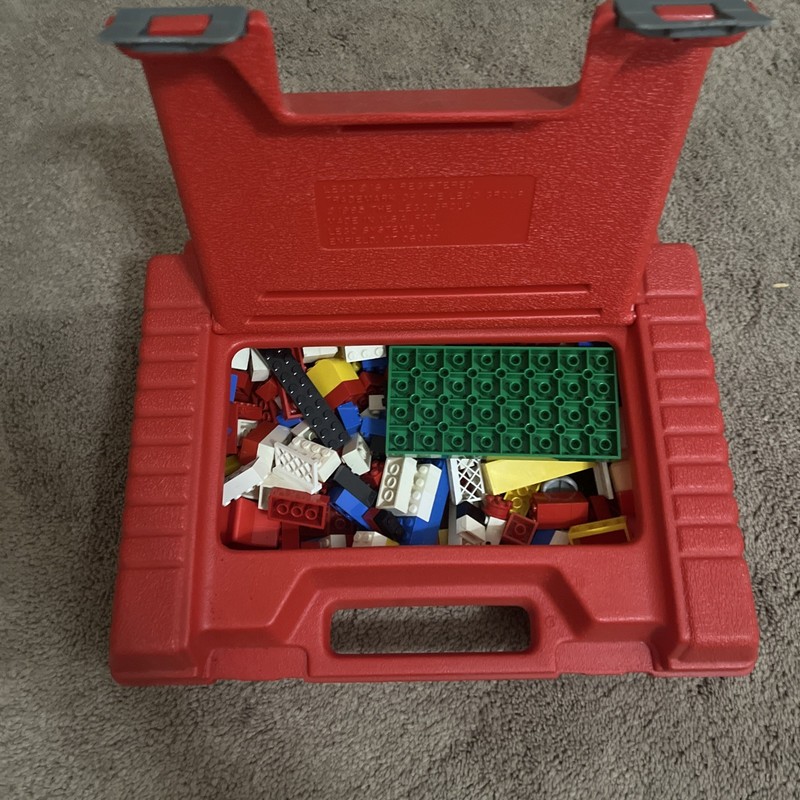 1985 LEGO red plastic storage and carrying case with assorted LEGO pieces.