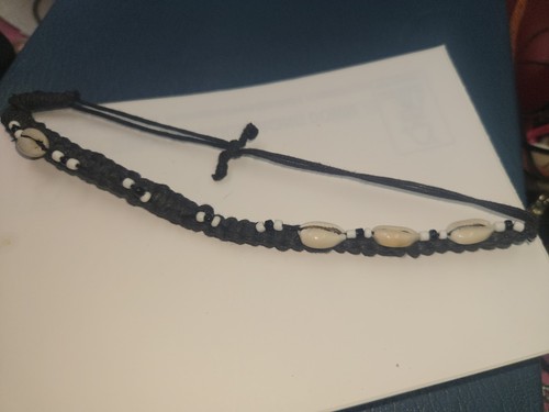 black woven necklace features natural cowrie shells and small white beads with a