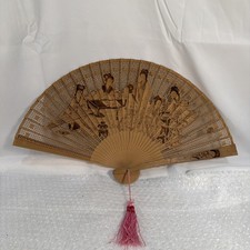 Chinese-style intricately carved sandalwood folding hand fan with a pink tassel
