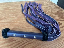Handmade flogger with a purple handle and three silver-colored studs and a ring