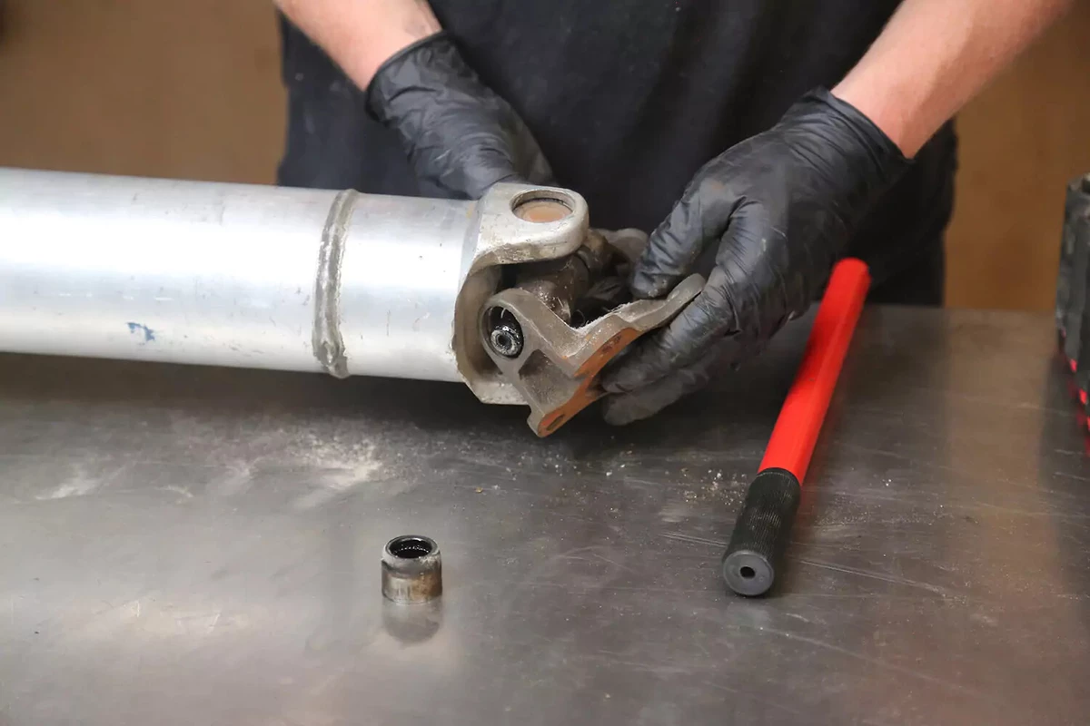 A mechanic wearing black gloves removes the yoke.