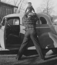 1950s Mystery Man Holding Baby Lifted Above Car Candid Family Moment From Behind