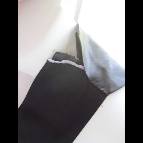 Black kids’ dress vest with white lace trim, button closure, and visible seam flaws on a white background.