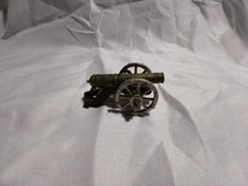 A decorative miniature metal cannon with spoked wheels and engraved barrel.