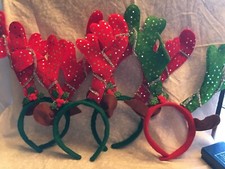4 reindeer headbands. 3 are green, 1 red bands with opposite color antlers.