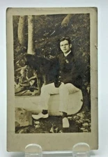 RPPC - Man Sitting on Edge of Canoe, Arm around his Dog