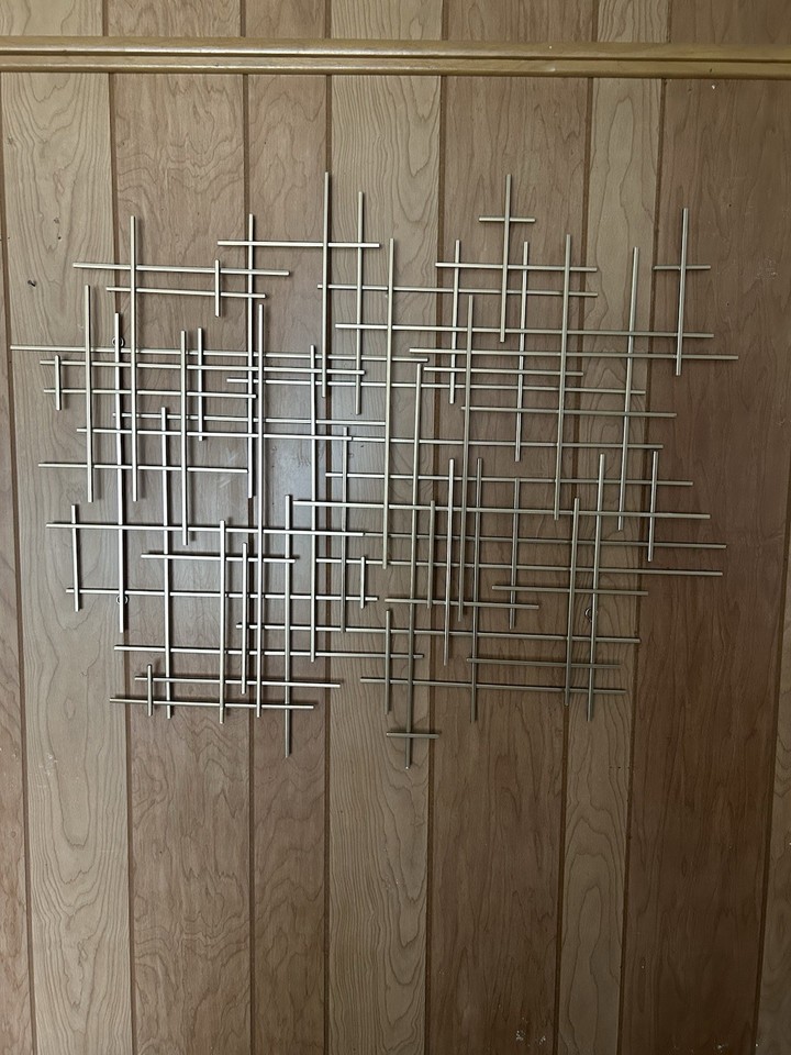 Brutalist geometric grid metal sculpture — the kind of serious, heavy mid-century abstract wall piece that anchors an entire room and stops guests cold.
