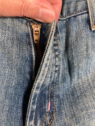 Close-up of blue stretch denim jeans with front zipper, brown stitching, and orange “Karen Kane Lifestyle” tag on waistband.