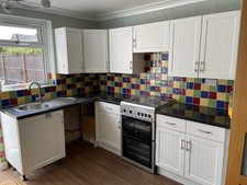 White Kitchen Units With Colourful Tiles Dark Worktop and Stainless Steel Sink