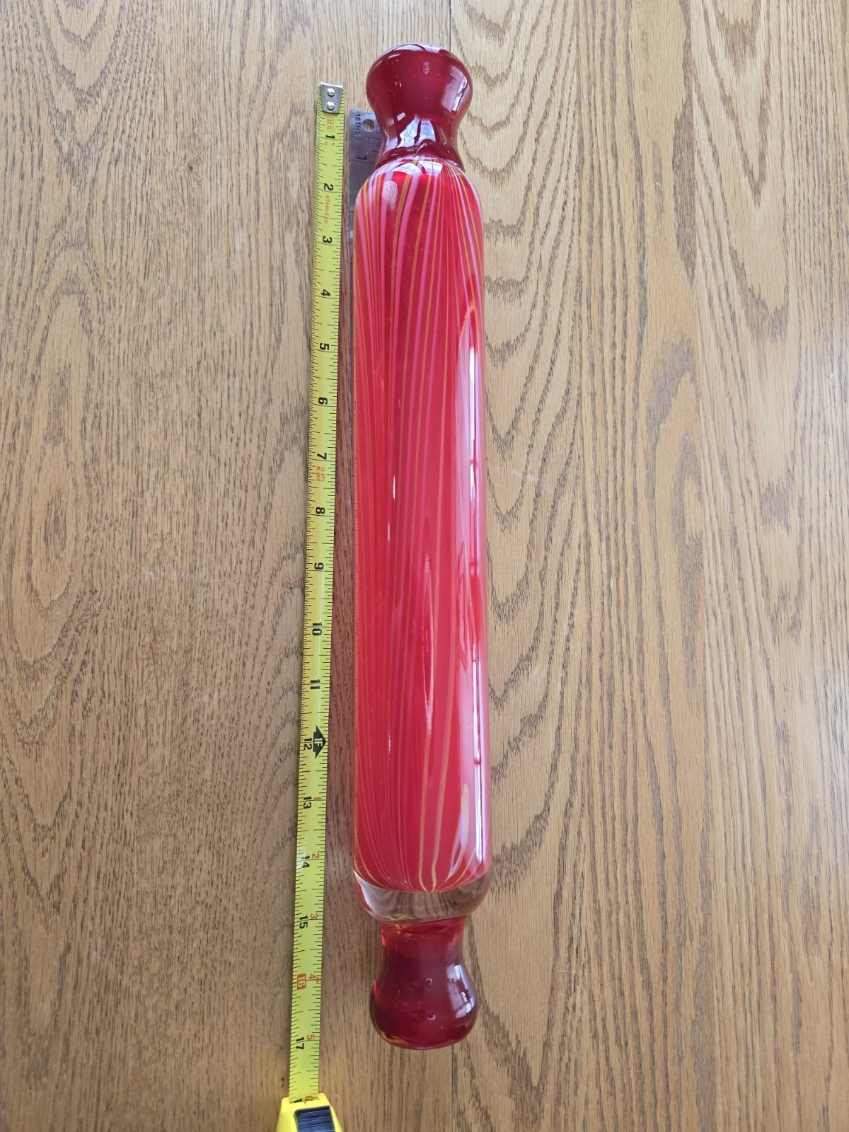 This is a red Murano-style art glass rolling pin with yellow swirl accents.