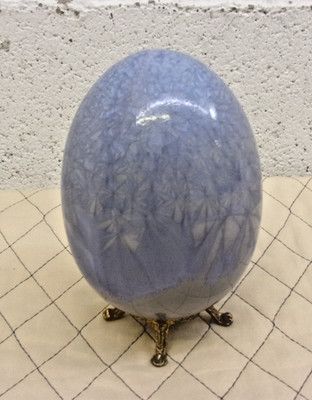 Decorative crystalline glazed egg on a golden stand.