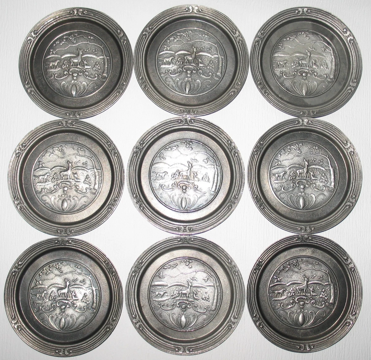 Neunteiliges Zinn-Untersetzer-Set mit detaillierten Relief-Jagdmotiven (Rehe, Ja