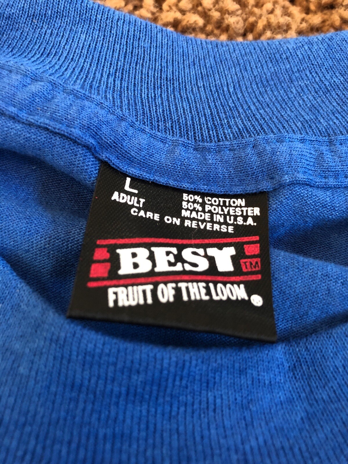 Blue short-sleeve shirt with white “EU” label, red “Fruit of the Loom” text, and USA Made stamp.
