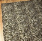 Brown leopard print cotton full flat sheet with black spots, laid flat on a wooden floor.