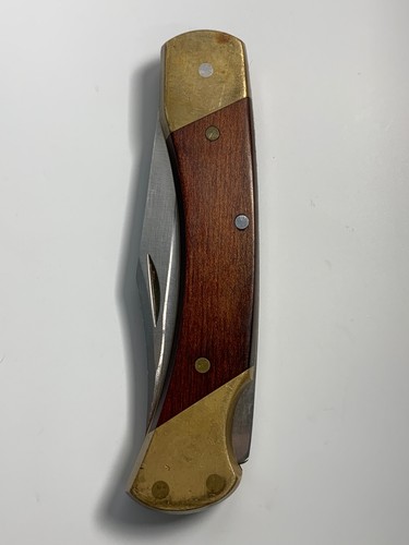 Vintage Schrade Uncle Henry LB 7 lockback with brass handle, wooden panel, and silver bolsters on a white background.