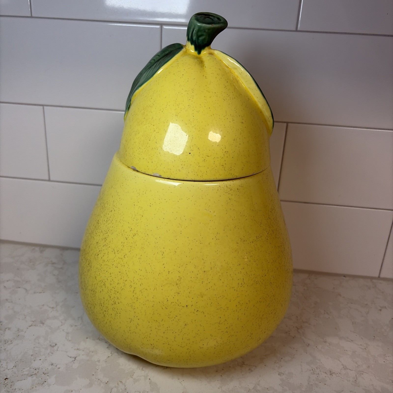 Yellow ceramic pear-shaped cookie jar with green stem lid.