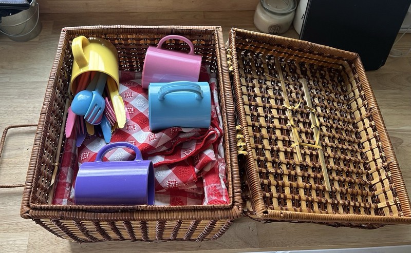 Vintage wicker picnic basket with plates, utensils, blanket and tablecloth
