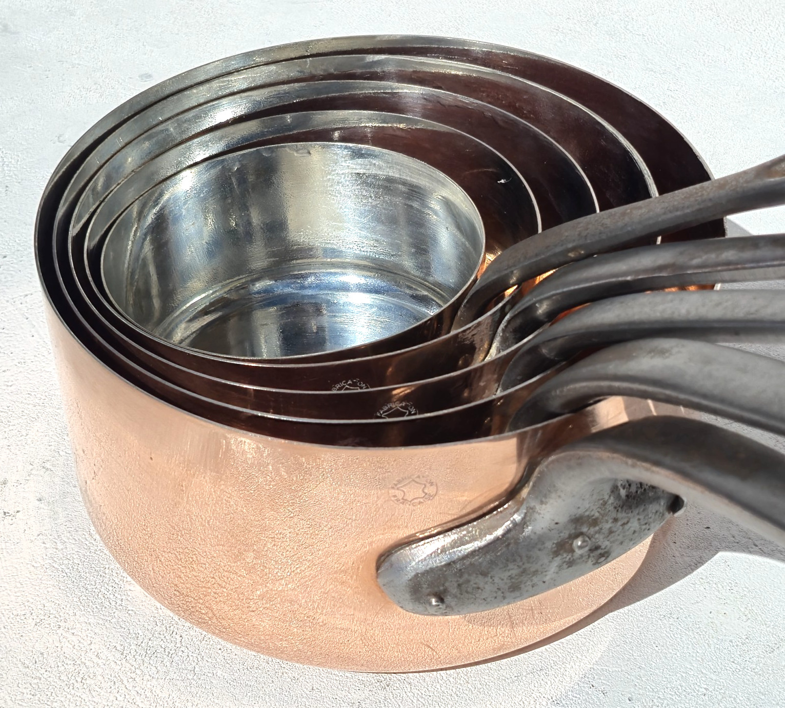 Set of five vintage French copper pans with tin lining, graduated sizes.