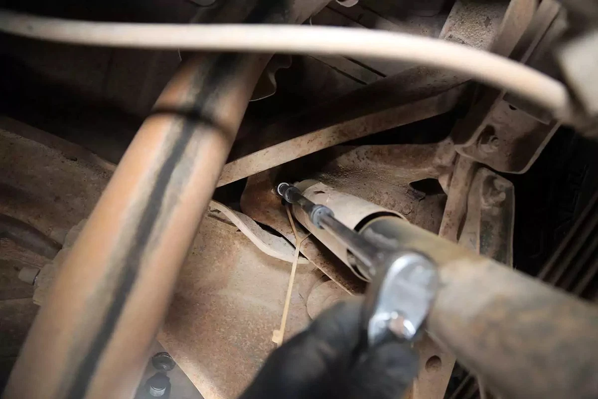 The upper shock bolt is removed with a socket wrench and extensions.