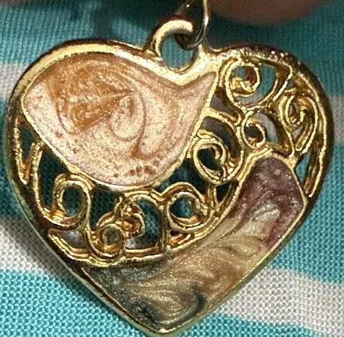 Gold-tone dangle drop heart pendant with filigree swirl and two enamel heart accents on a teal fabric background.