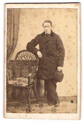 Fotografie Portrait junger Mann im Mantel mit Hut in der Hand 