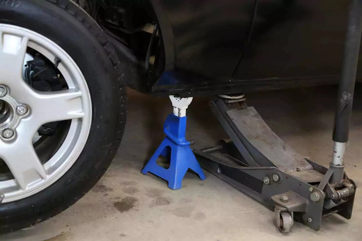 A vehicle lifted with a jack stand and a floor jack.