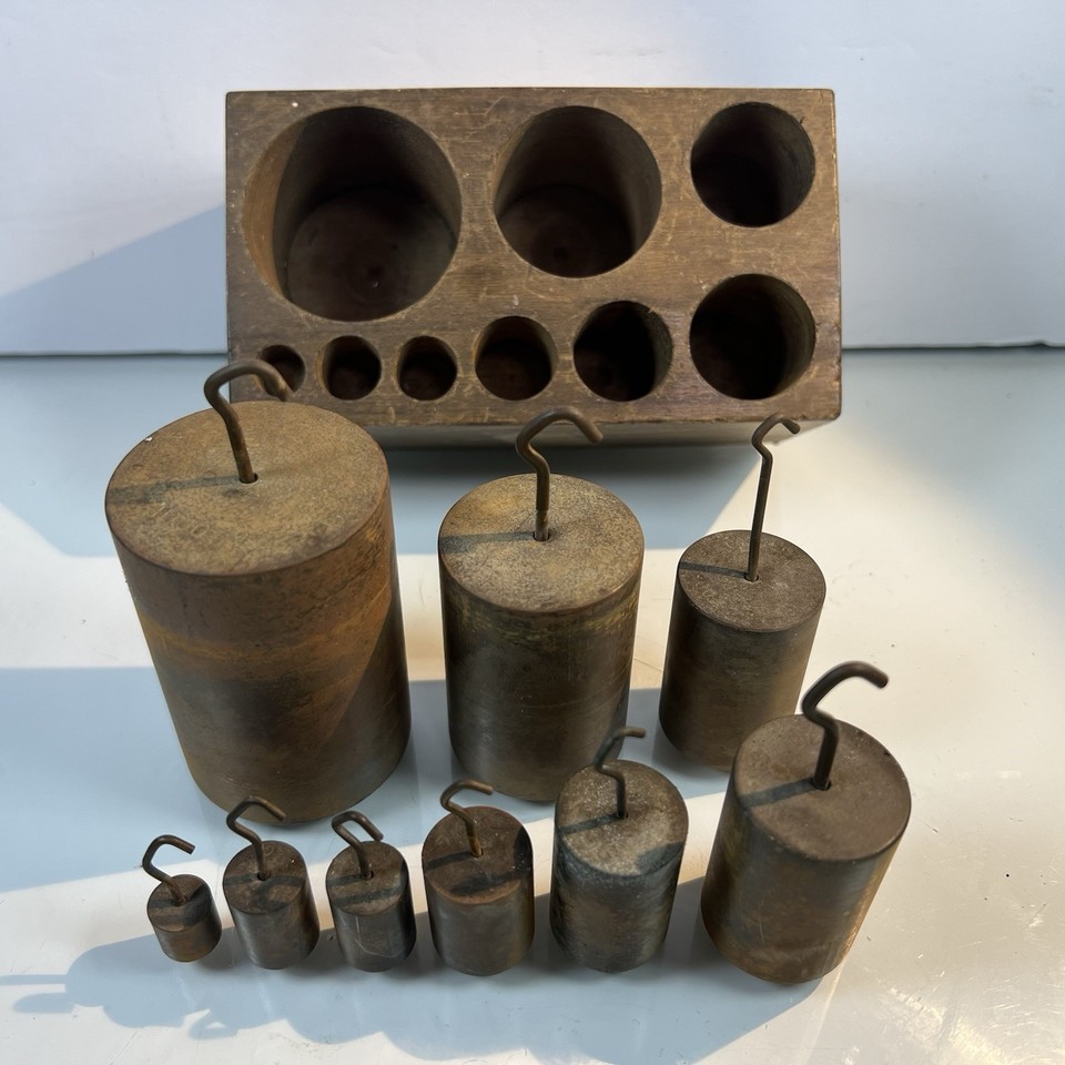 A museum-worthy 9-piece brass apothecary weight set nested in a fitted wooden block — the kind of tactile, handsome object that stops guests in their tracks.