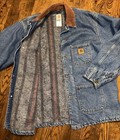 Blue denim Carhartt C59DST chore coat with brown collar, front pocket, and visible Carhartt logo patch on chest.