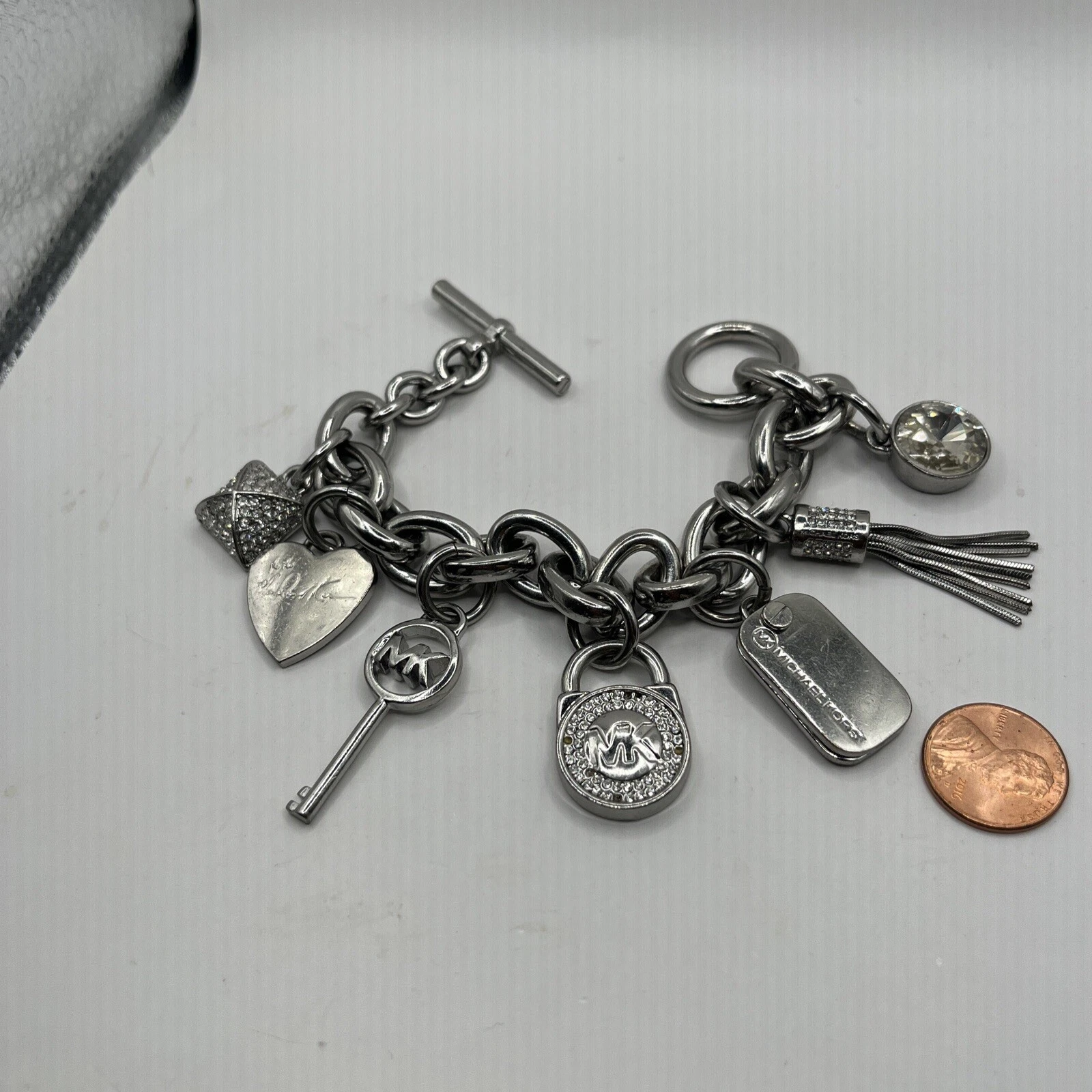 Bracciale Michael Kors tono argento strass charm toggle pietre mancanti
