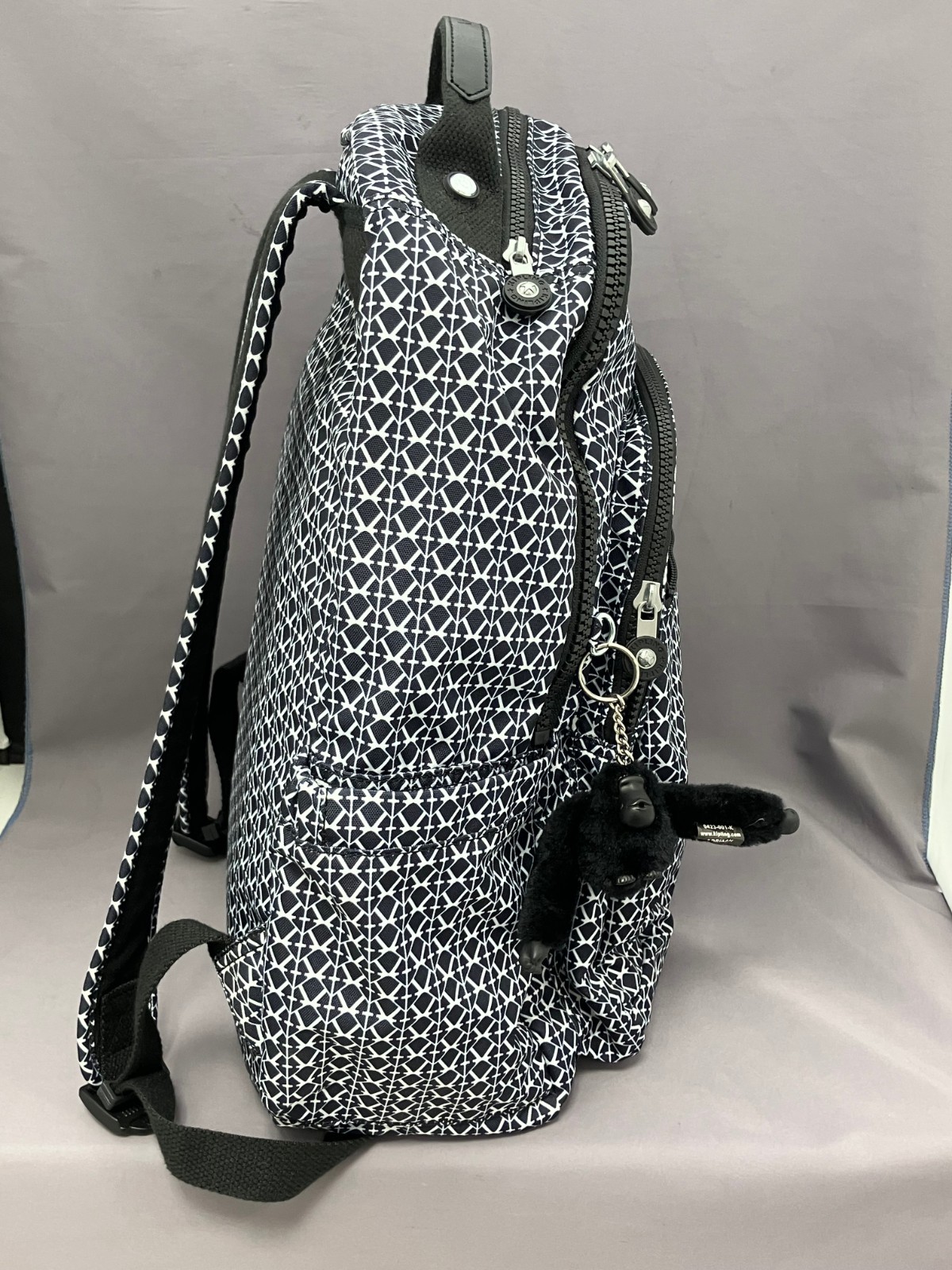 Black and white geometric print Kipling Seoul backpack with front zipper, monkey keychain, and textured fabric.