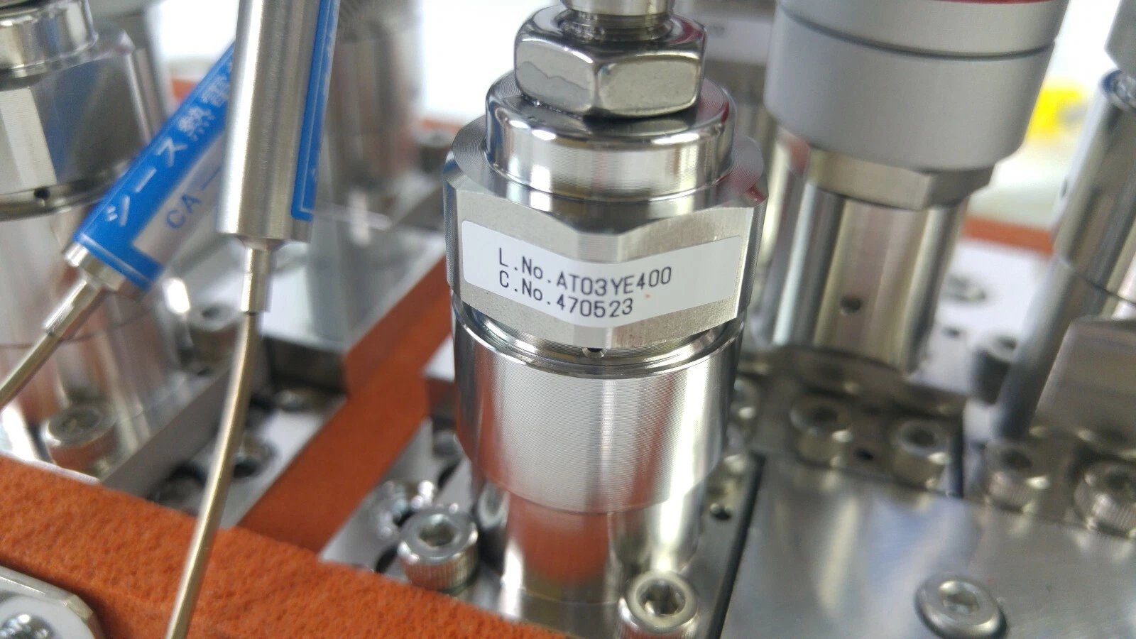 Fujikin valve body with lot-number label next to a sheathed thermocouple probe