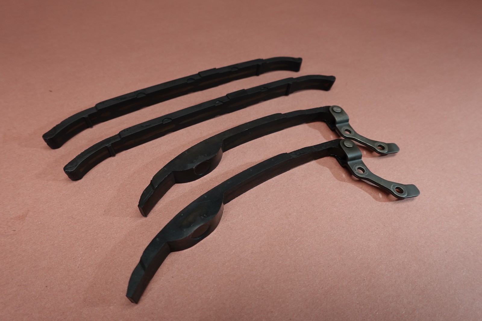 Black 1998-2015 Yamaha VStar V Star 650 XVS650 cam shaft timing chain guides with bent-over design on a brown surface.