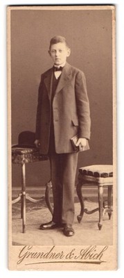 Fotografie Grundner & Abich, Berlin, Portrait junger Mann im Anzug mit einem Bu 