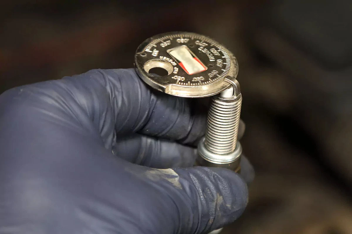 Spark plug gapping tool being used to verify the correct plug gap.