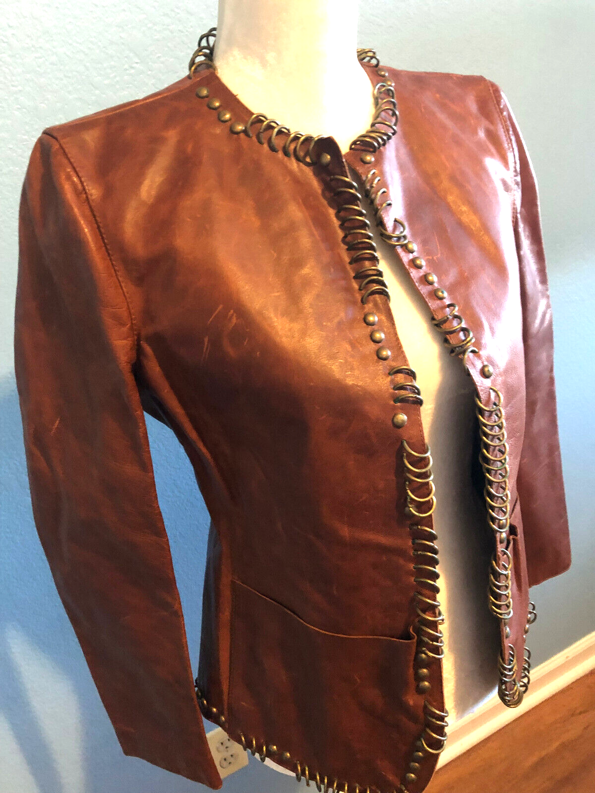 Giacca in pelle cognac design Yves Saint Laurent Tom Ford con anelli in ottone