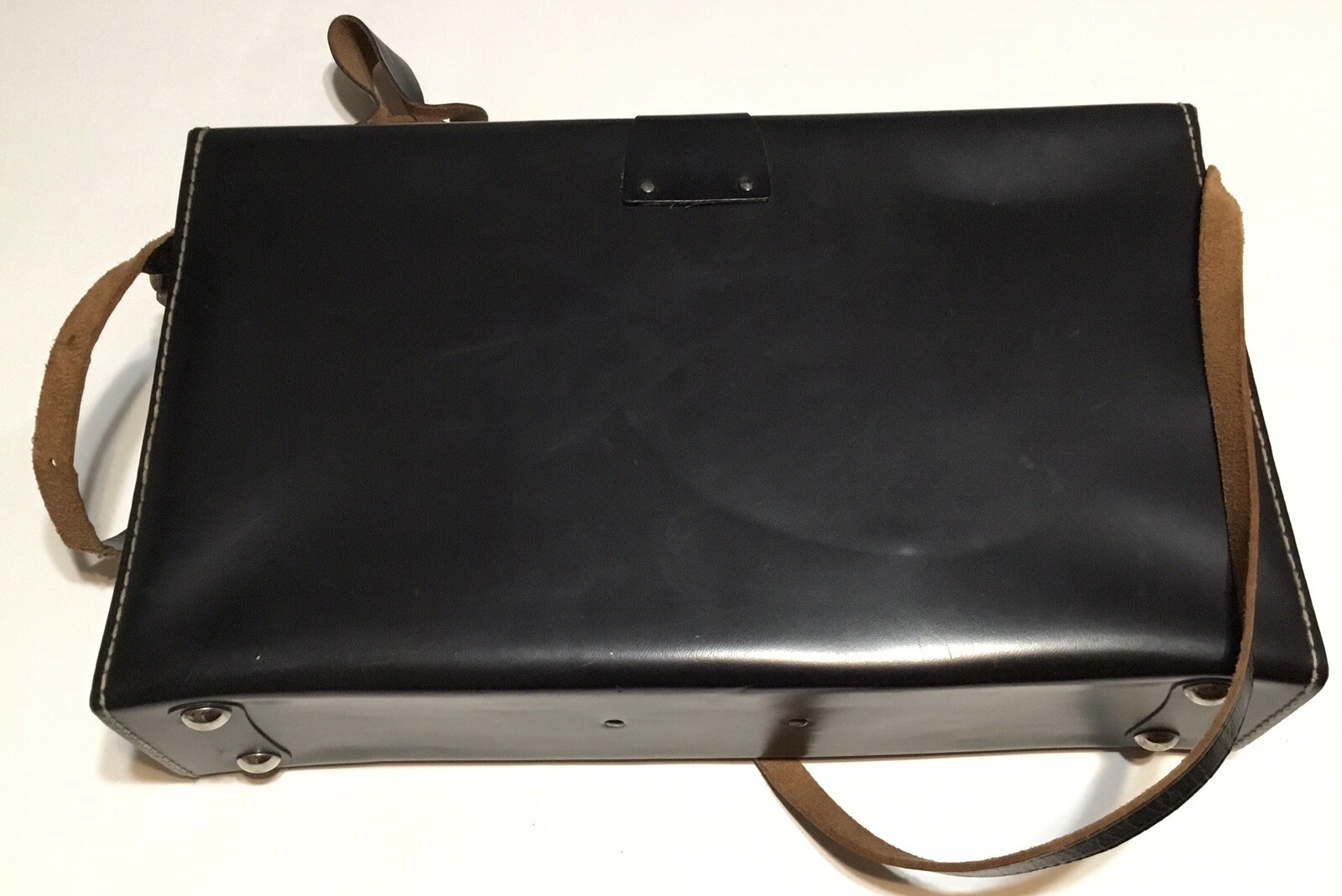Black leather shoulder bag with visible seams, brown adjustable strap, and “Made in U.S.A.” text on top.