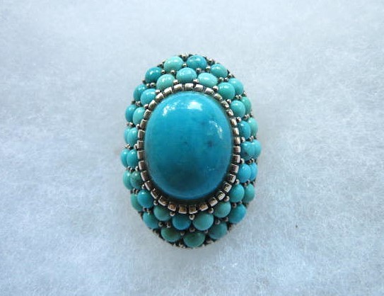 A  SPLENDID TURQUOISE AND STERLING DOMED AND ROWED RING SX.925
