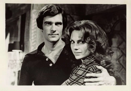 Black and white 5x7 photo of Tom Hallick and Janice Lynde in embrace, with plaid shirt and dark hair details.