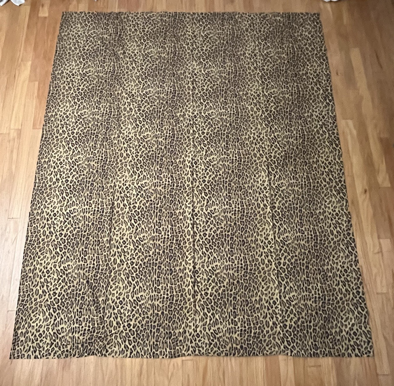 Brown leopard print cotton flat sheet with intricate textured pattern, displayed on a light wood floor.
