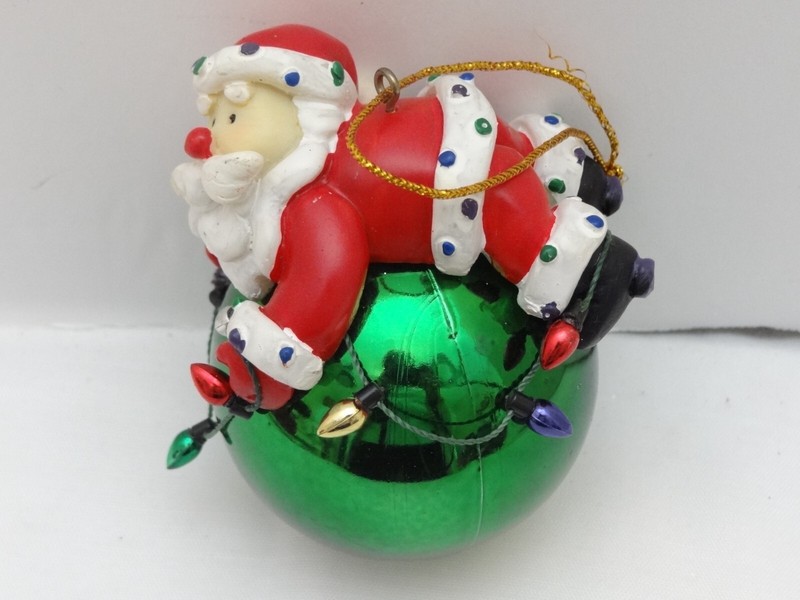 Santa laying on String of Lights & Green Ball Christmas Ornament