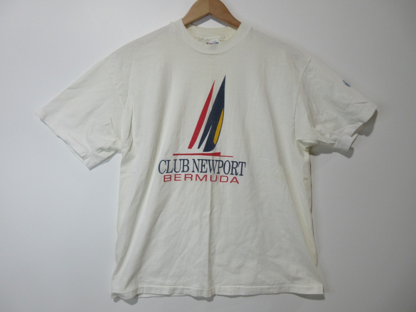 White short-sleeve T-shirt with red and black Club Newport Bermuda logo and navy swoosh on left chest, USA MADE text below.