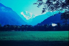 RED BORDER SLIDE Green field, blue mountains, white hotel & snowy peaks.