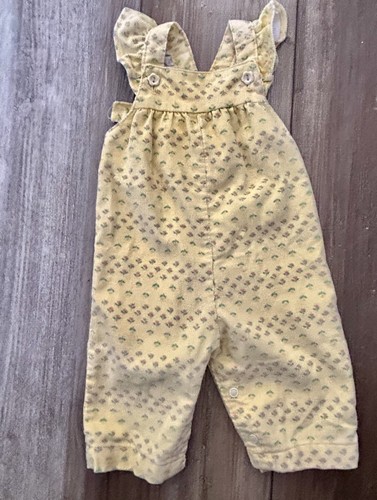Yellow corduroy baby romper with light gray floral print, long sleeves, front buttons, and adjustable straps.