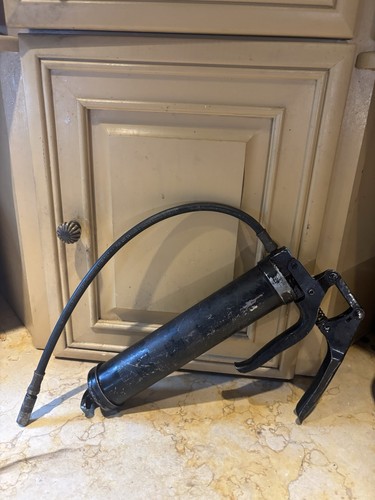 heavy-duty, black metal grease gun with a pistol-grip handle designe