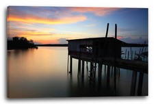 Canvas/Frames Wooden walkway with cottage on stilts in the water, above sunset