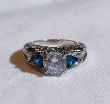 The ring is a vintage-style three-stone cubic zirconia engagement ring size 6