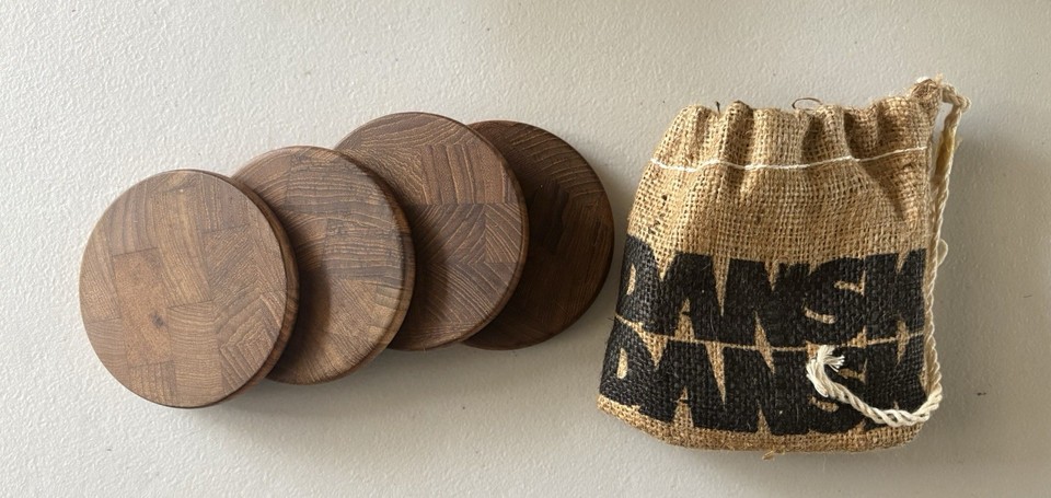 Four original Dansk teak coasters in their jute bag — a low-stakes way to own a piece of the most iconic MCM tableware brand, perfect as a stocking stuffer.